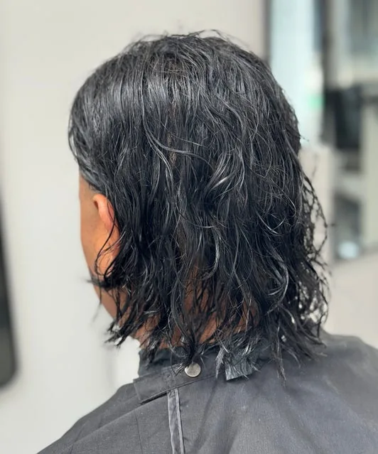 Haircut — back of head, long wavy cut with black cape