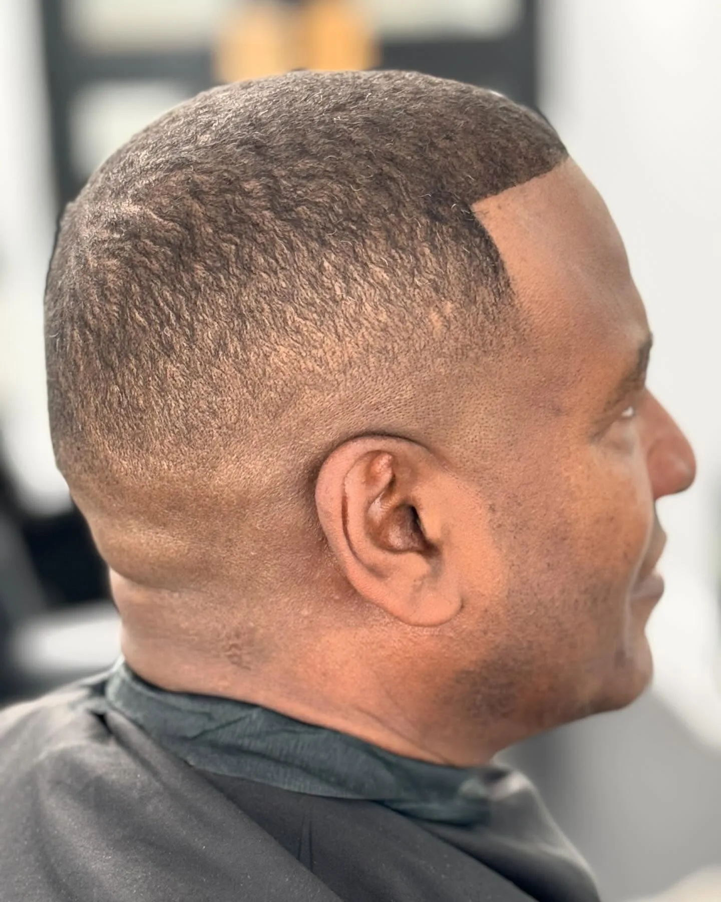 Caesar cut with beard trim, caped client, bright salon behind